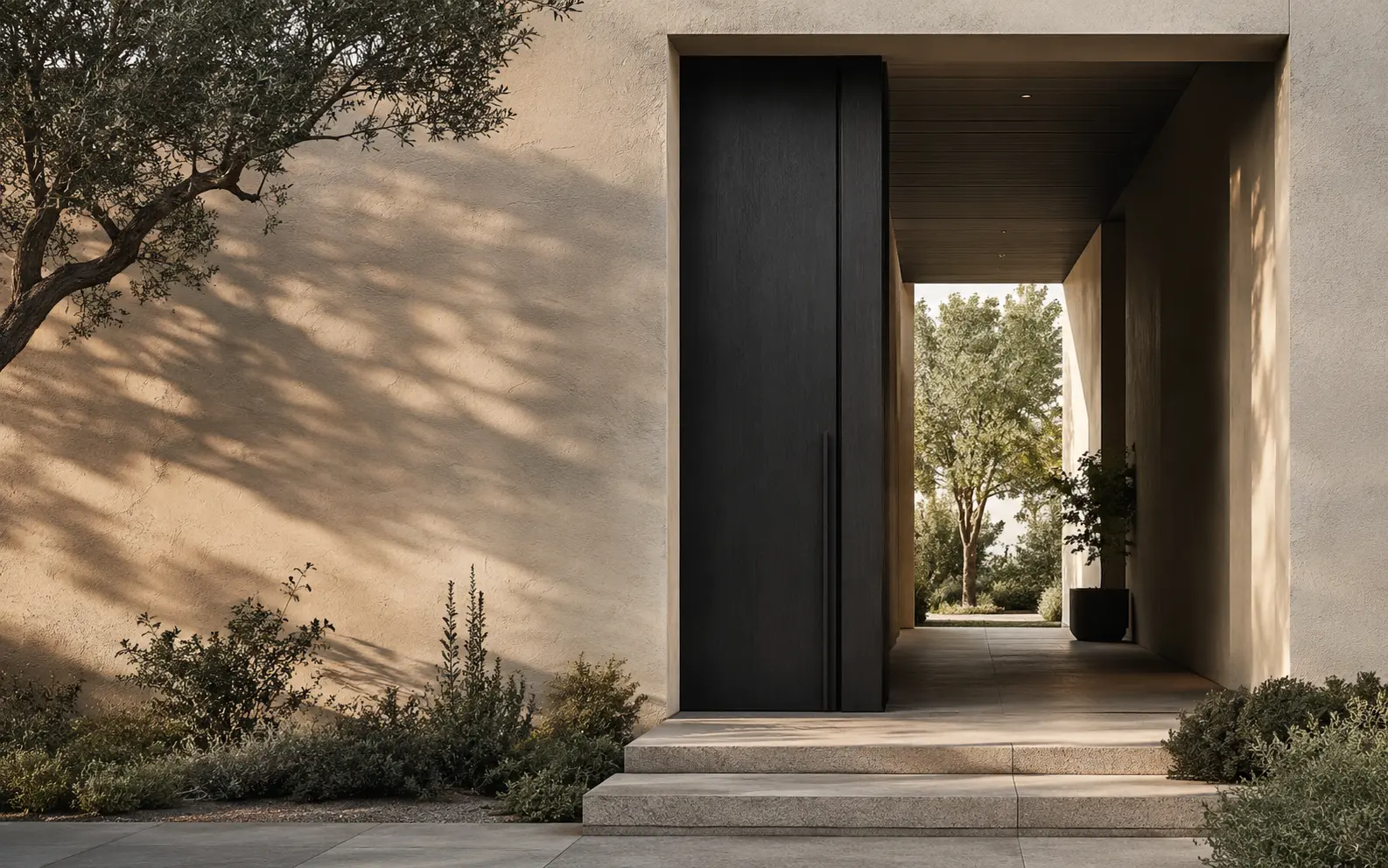 Contemporary private residence entrance framed by stone walls, mature planting and warm natural light.